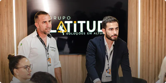 Equipe do Grupo Latitud reunida na sede da empresa diante do painel da marca