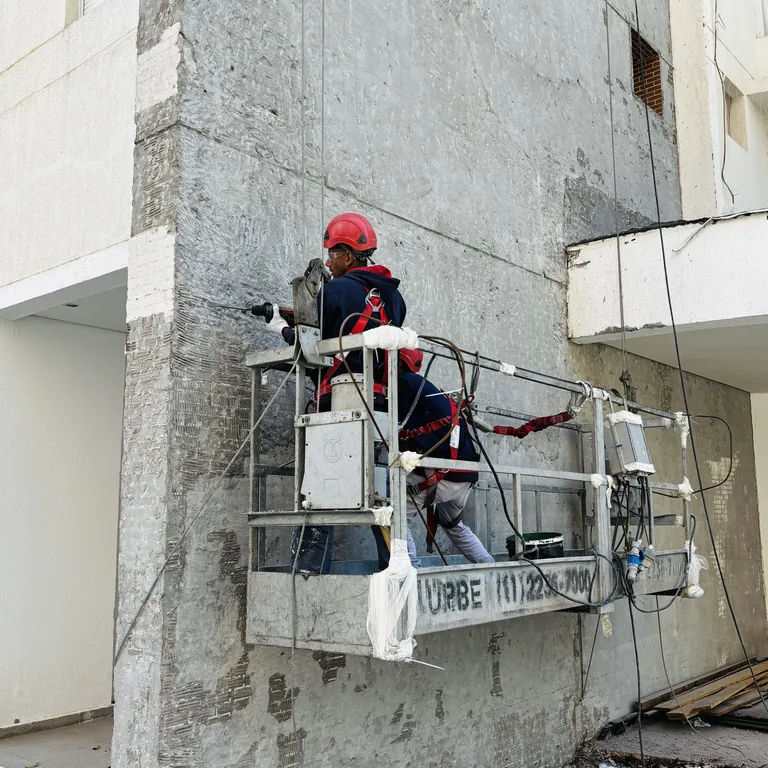 Retrofit de fachada predial com equipe em plataforma elevatória